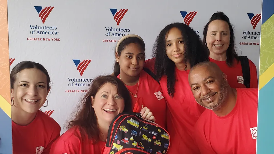 McGraw Hill employees volunteering for Operation Backpack in from of Volunteers of America sign