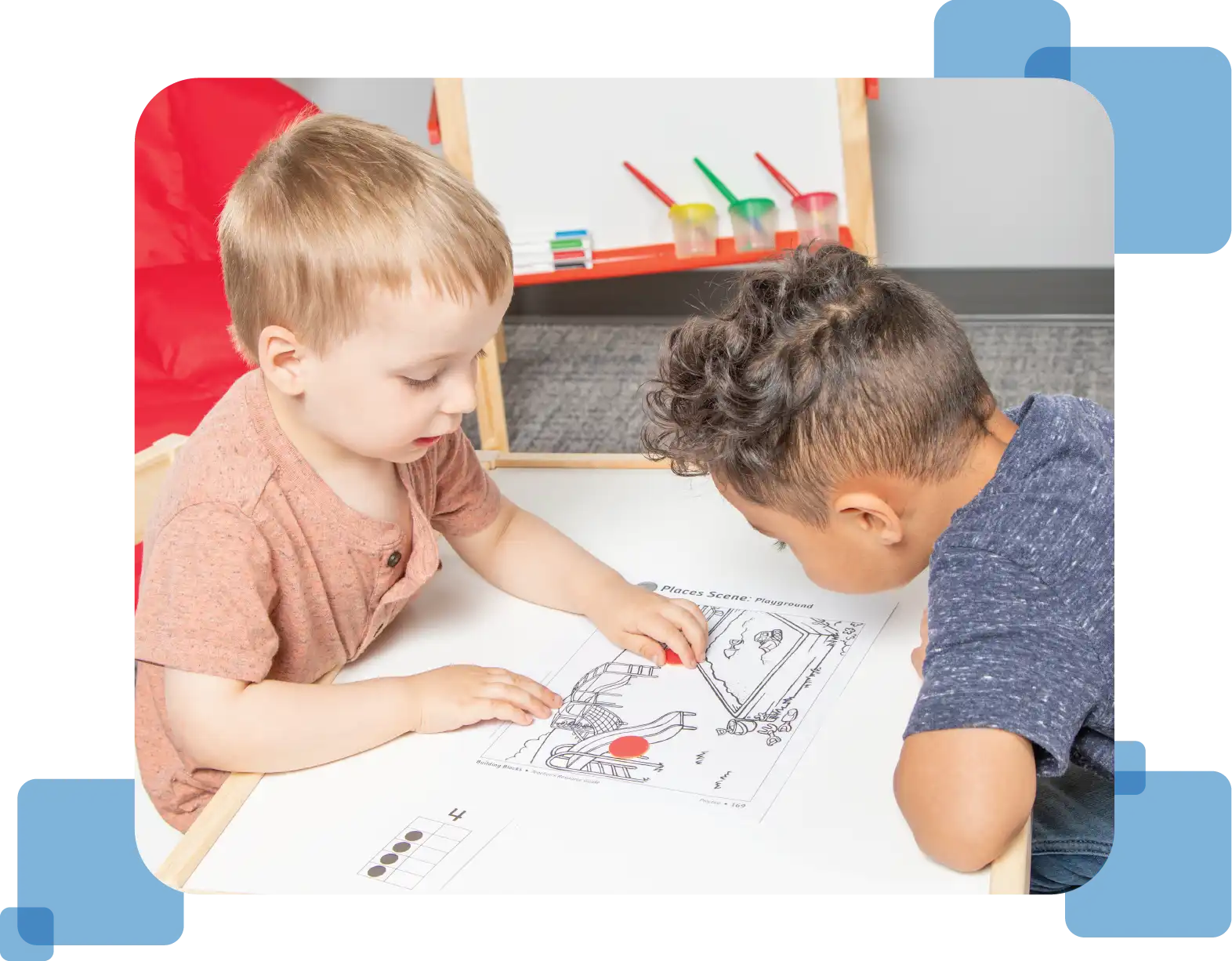 Two young children examine a paper print-out of a playground from the Teacher’s Resource Guide.