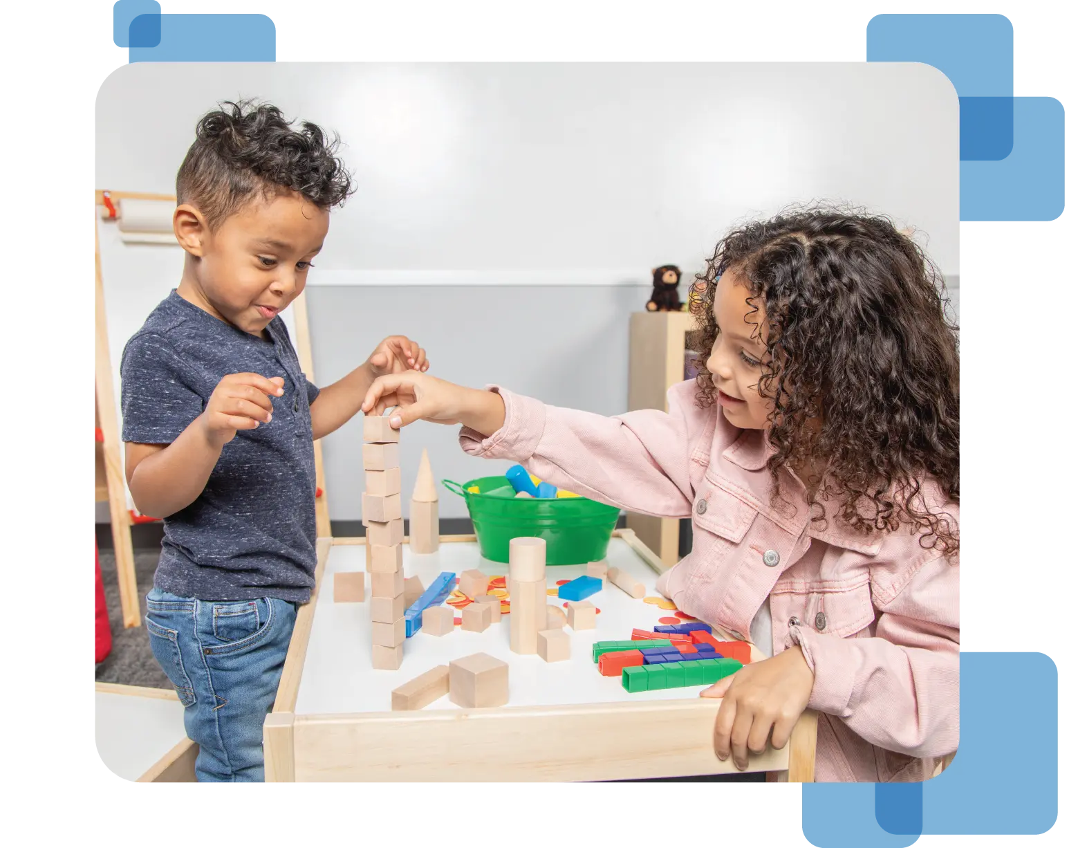 Two young children stack geometric wooden blocks together