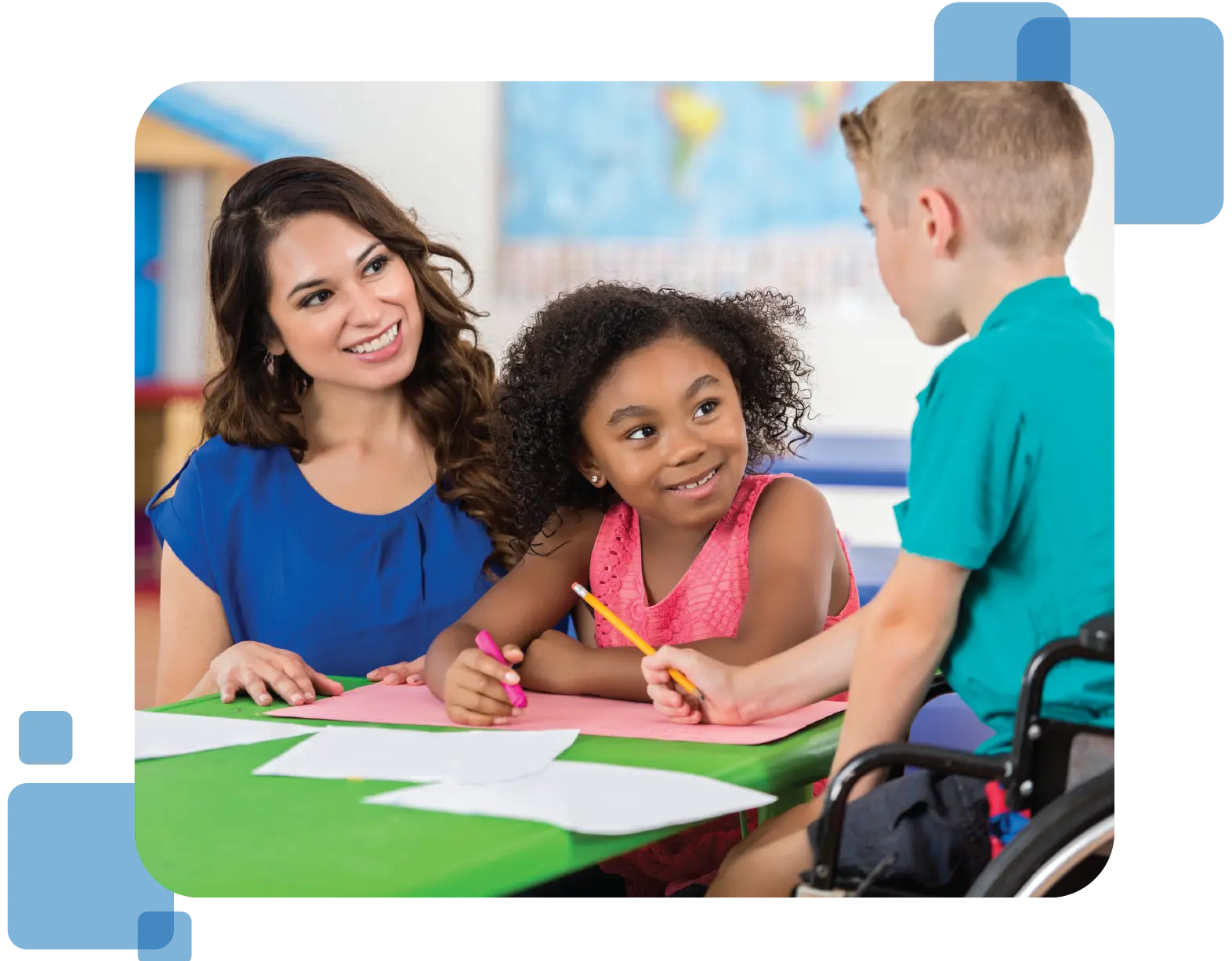 A young child with a pencil in hand speaks to a teacher and  classmate while they listen intently.