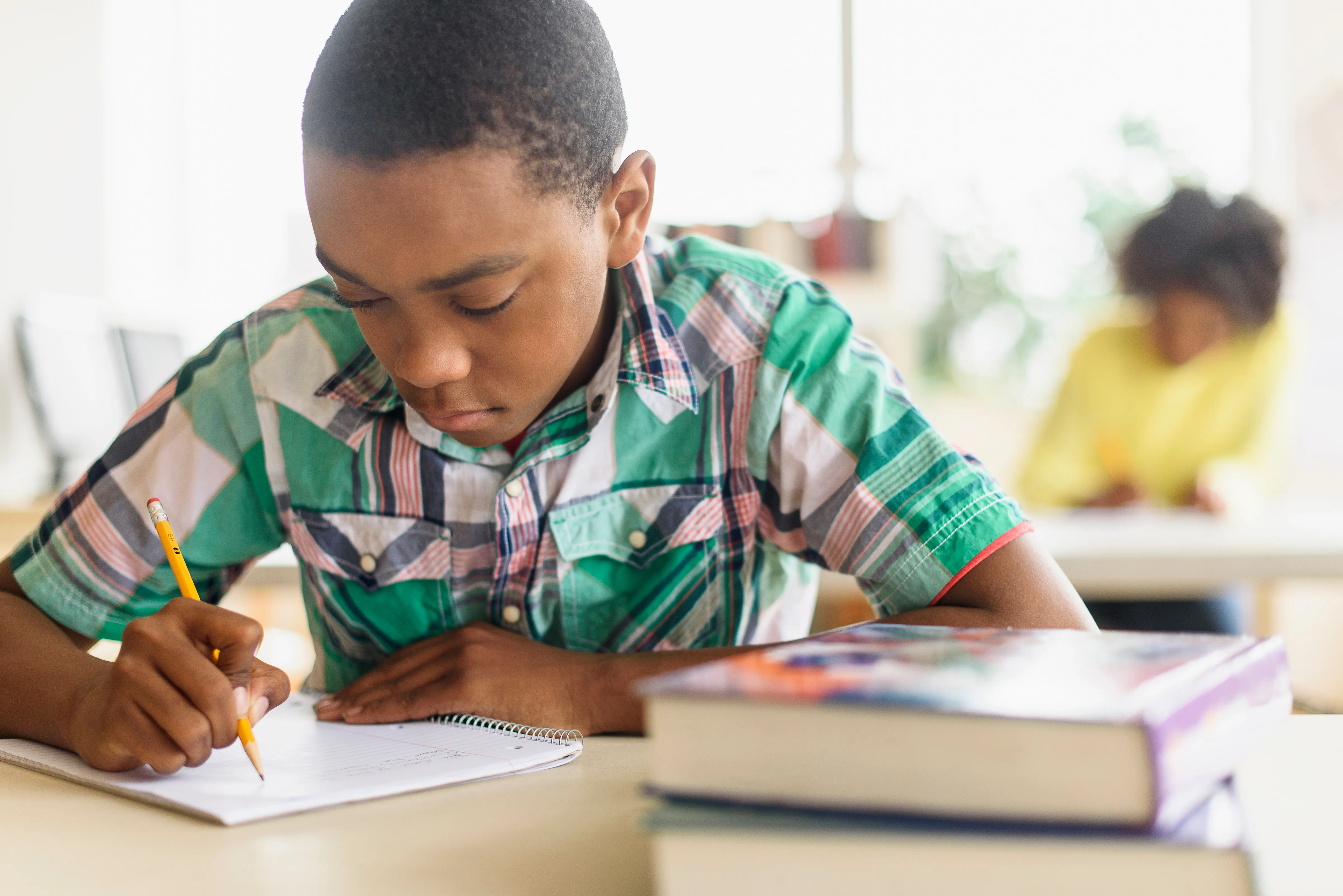 Student in class writing on paper with pencil