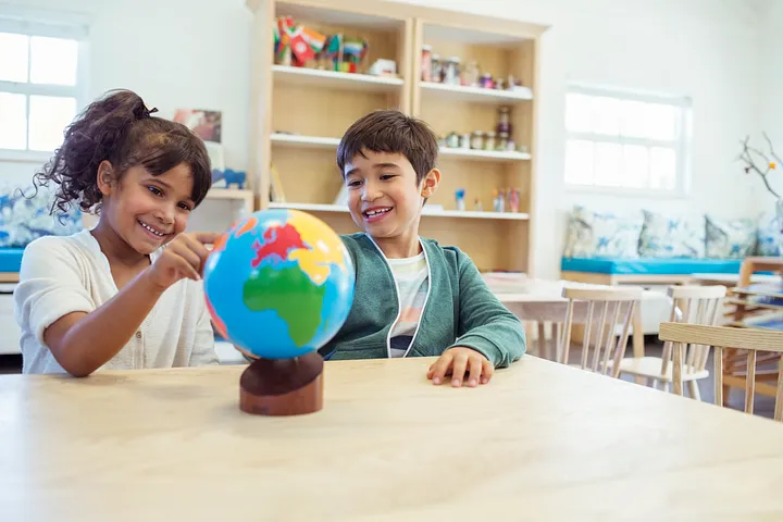 Students in classroom setting looking at a globe