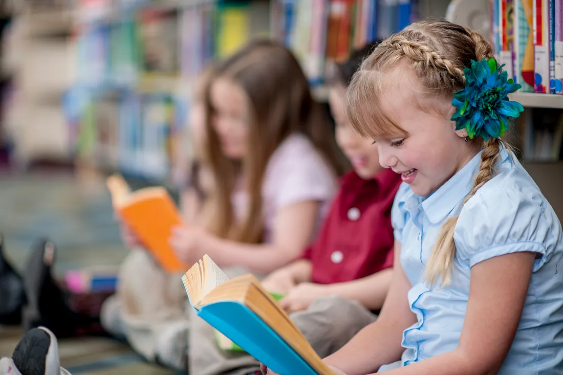young students reading books in a library setting